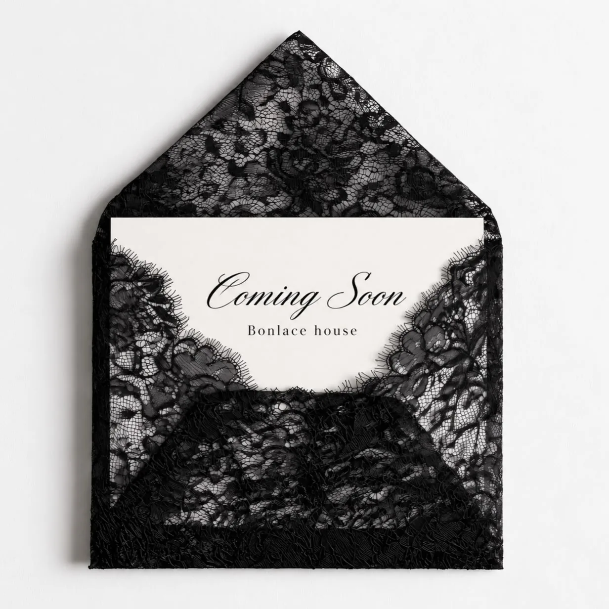 A black lace envelope holding a card that reads Coming Soon